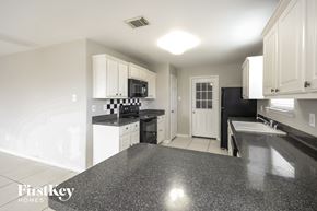 Richmond house for rent - a kitchen with white cabinets and black counter tops