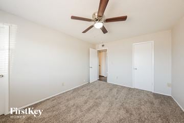 Peoria house for rent - a spacious living room with carpet and a ceiling fan