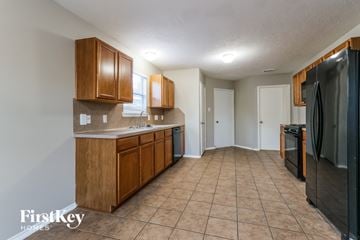 Magnolia house for rent - A kitchen with wooden cabinets and a black refrigerator.