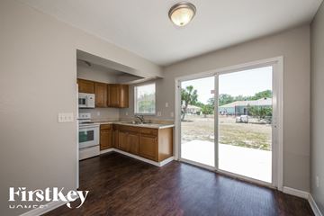 North Port house for rent - A kitchen with wooden cabinets and a view of a parking lot through the sliding glass doors.