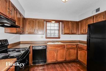Memphis house for rent - A kitchen with wooden cabinets and a black refrigerator.