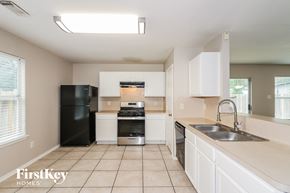 Cypress house for rent - a kitchen with white cabinets and black appliances
