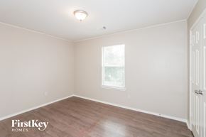 Cypress house for rent - a bedroom with wood floors and white walls and a window