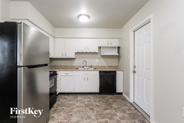 Indianapolis house for rent - A kitchen with a black refrigerator and white cabinets.