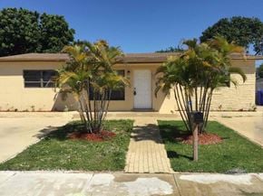 Hollywood house for rent - A house with a white door and two palm trees in front.