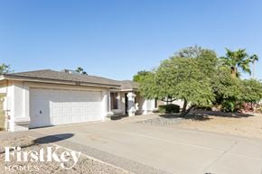 Peoria house for rent - A house with a garage and a tree in front of it.