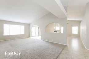 Glendale house for rent - A spacious, empty room with a carpeted floor and large windows.