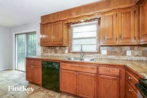 Raytown house for rent - a kitchen with wooden cabinets and a sink and a window