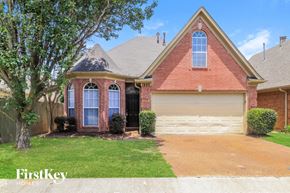 Cordova house for rent - A brick house with a garage door and a tree in front.