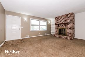 Kansas City house for rent - the living room has a brick fireplace and carpeted flooring