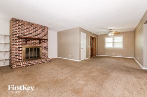 Kansas City house for rent - a living room with a brick fireplace and a carpeted floor