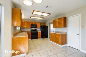 Houston house for rent - a kitchen with wooden cabinets and a white tile floor