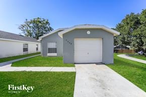 Orlando house for rent - a gray house with a white garage door and a lawn