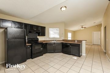 Orlando house for rent - a kitchen with black cabinets and a sink and a refrigerator