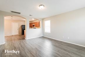 Humble house for rent - A spacious room with wooden flooring and a kitchen area in the background.