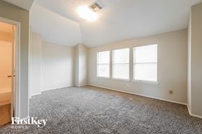 Humble house for rent - A spacious room with a grey carpet and a window.