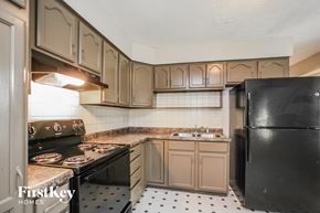 Indianapolis house for rent - a kitchen with white cabinets and black appliances and a black refrigerator