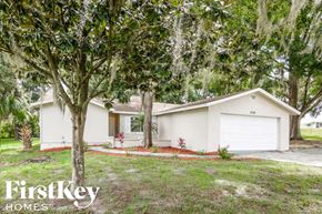 Lakeland house for rent - A white house with a garage is surrounded by greenery.