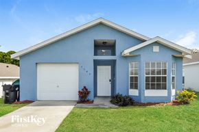 Orlando house for rent - a blue house with two garage doors and a lawn