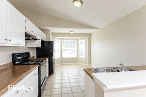 Orlando house for rent - a kitchen with white cabinets and black appliances and a sink