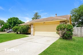 Houston house for rent - A yellow house with a garage door and a tree in front.