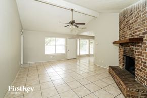 Houston house for rent - A spacious living room with a brick fireplace and a ceiling fan.