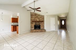 Houston house for rent - A spacious living room with a brick fireplace and a fan on the ceiling.