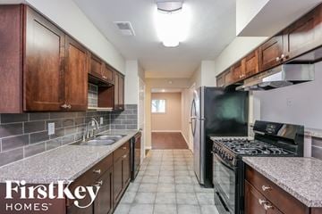 Dallas house for rent - a kitchen with granite counter tops and wooden cabinets and black appliances