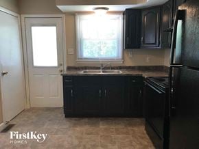 Indianapolis house for rent - a kitchen with black cabinets and a sink and a door