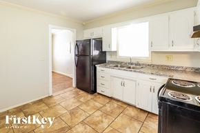Kansas City house for rent - A kitchen with a black fridge and white cabinets.