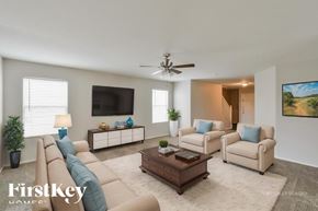San Antonio house for rent - A living room with a beige sofa, two armchairs, a coffee table, and a flat-screen TV mounted on the wall.