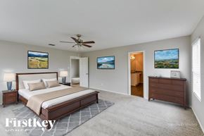 San Antonio house for rent - A bedroom with a large bed, a ceiling fan, and two paintings on the wall.
