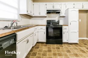 Kansas City house for rent - a kitchen with white cabinets and black appliances