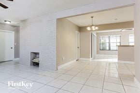 Miramar house for rent - an empty living room with a brick fireplace and tiled flooring