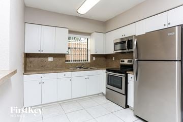 Miramar house for rent - a kitchen with white cabinets and stainless steel appliances
