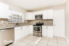 Miramar house for rent - a kitchen with white cabinets and stainless steel appliances