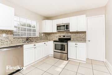 Miramar house for rent - a kitchen with white cabinets and stainless steel appliances