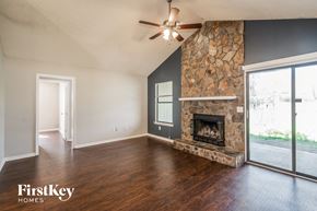 Jacksonville house for rent - A spacious living room with a stone fireplace and a ceiling fan.