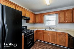 Winston house for rent - a kitchen with wooden cabinets and a black refrigerator