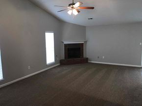 Southaven house for rent - an empty living room with a fireplace and a ceiling fan