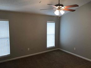 Southaven house for rent - an empty bedroom with a ceiling fan and two windows