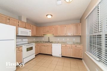Bessemer house for rent - a kitchen with white appliances and wooden cabinets