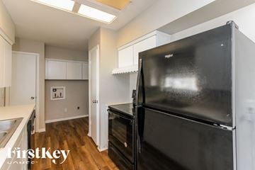 Dallas house for rent - a kitchen with a black refrigerator and white cabinets