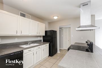 Fort Worth house for rent - a kitchen with white cabinets and a black stove and refrigerator