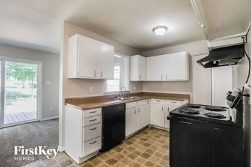 Kansas City house for rent - a kitchen with white cabinets and black appliances and a window