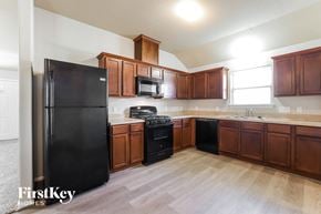 Texas City house for rent - a kitchen with wood flooring and wooden cabinets and black appliances