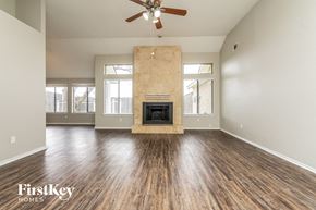 Rowlett house for rent - an empty living room with a fireplace and a ceiling fan