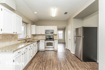 Rowlett house for rent - a kitchen with white cabinets and stainless steel appliances