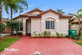 Hialeah house for rent - a house with a driveway and palm trees