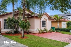 Hialeah house for rent - a home with a pink exterior and palm trees